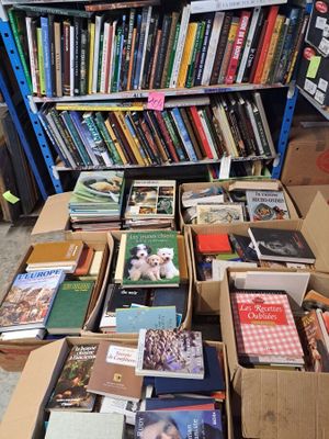 boxes of books are stacked on a table in front of a bookshelf