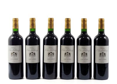 six bottles of wine are lined up on a white surface