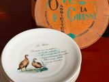 a stack of plates sitting on a table with a clock in the background