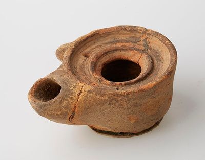 un vase marron troué posé sur une surface blanche