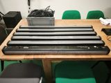 quatre enceintes noires posées sur une table en bois, avec une chaise verte devant elles