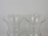 two clear glass vases sitting on a white surface