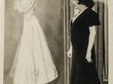 black and white photograph of a woman standing next to a painting of a woman in a dress