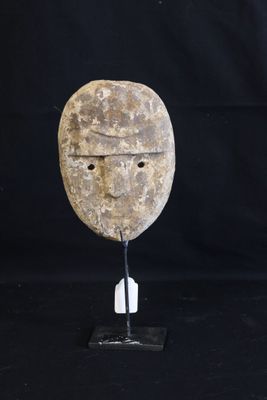 a close up of a stone mask on a stand on a black background