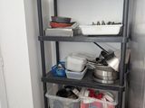 une étagère sur laquelle sont posés des casseroles et des poêles, dans un coin de la pièce