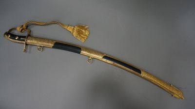 a gold plated sword with a black handle on a gray background