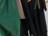 two green and black capes on a mannequin stand in a store