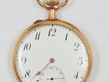 gros plan d'une montre de poche en or sur une surface blanche