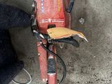 une tondeuse de couleur terre rouge posée par terre à côté d'une chaise noire