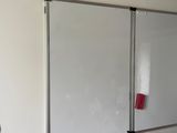 a whiteboard in the corner of a room with a red marker on it