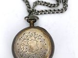 a silver pocket watch with a chain on a white surface