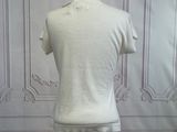 a white shirt on a mannequin stand in front of a wall
