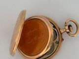 a gold pocket watch with a brown dial on it