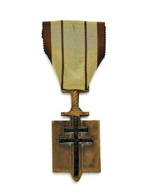 une vieille médaille avec une croix au recto et un ruban au verso