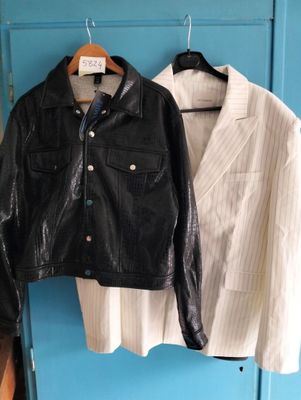 two jackets hanging on a blue wall next to a pair of shoes