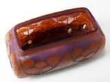a purple and orange glass container with a brown handle
