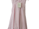 une robe rose suspendue à un cintre sur un mur blanc