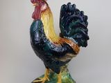a figurine of a rooster on a green base