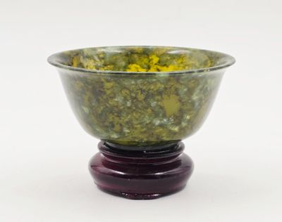 un bol vert contenant des fleurs jaunes, posé sur un socle en bois