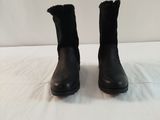 pair of black boots on a white bed with a white sheet