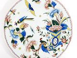 a white plate with blue and yellow flowers and birds on it