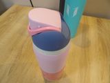 a pink and blue cup sitting on a table next to a blue and pink box
