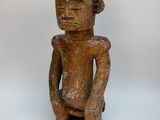 une vieille statue en bois d'un homme avec un chapeau sur la tête