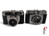 two old cameras sitting side by side on a white surface