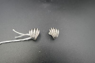 paire de boucles d'oreilles en forme de fleurs plaquées argent sur un fond noir