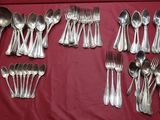 un grand nombre de cuillères et de fourchettes en argent disposées sur une table