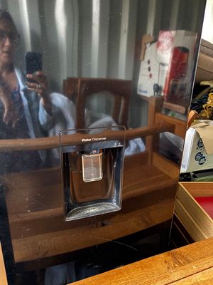 reflection of a woman in a mirror on a desk with a coffee maker