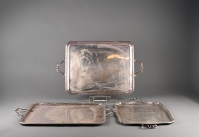 three silver trays sitting on a stand on a gray surface