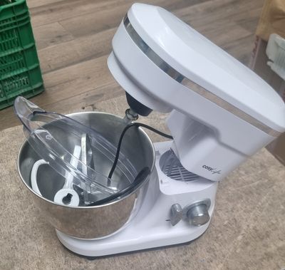 a mixer sitting on the floor next to a bowl of food