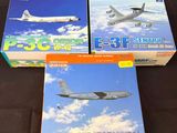 trois boîtes contenant des maquettes d'avions, posées sur une surface noire