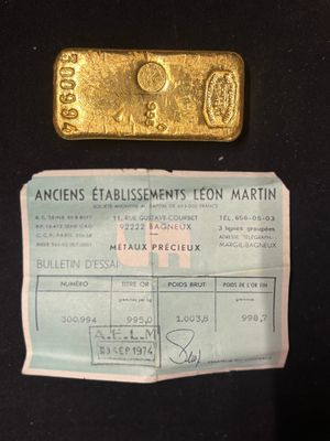 a piece of gold on a piece of paper next to a bar of gold