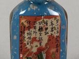 une bouteille en verre bleue décorée d'une peinture