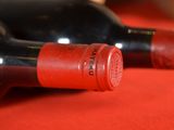 two bottles of wine sitting on a red cloth