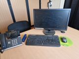 a desk with a computer, phone, and telephone on it