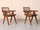 two wooden chairs sitting next to each other in a room