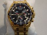 gold watch with black face and red hands on display in a store