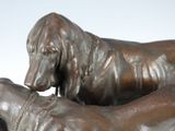 a bronze statue of a dog and a dog laying on top of each other