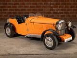 an orange model of a car parked in front of a brick wall