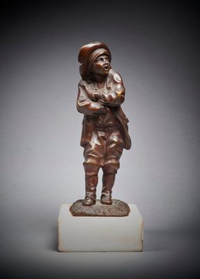 une statue en bronze représentant un garçon debout au sommet d'un bloc de marbre