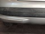 the front bumper of a silver car with a denting on it