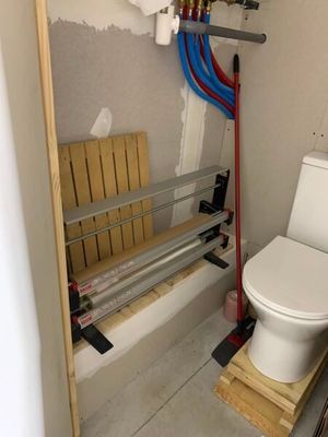 des toilettes dans une petite salle de bains, avec des tuyaux et un siège de WC