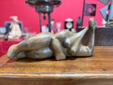 une statue en bronze représentant une femme allongée sur une table