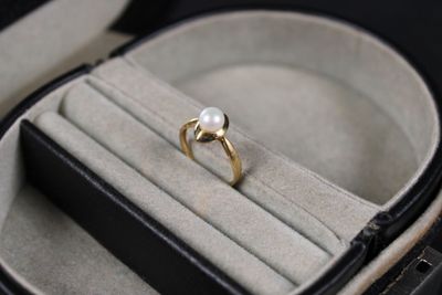 a ring in a case with a pearl inside of it