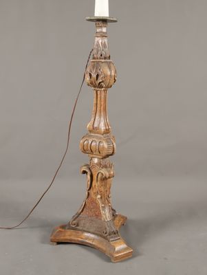 une lampe de table ancienne en bois sur laquelle est posée une bougie blanche