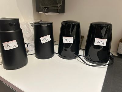 quatre enceintes noires posées sur un comptoir, sur lesquelles figurent des étiquettes