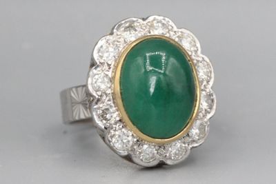 gros plan d'une bague avec une pierre verte entourée de diamants